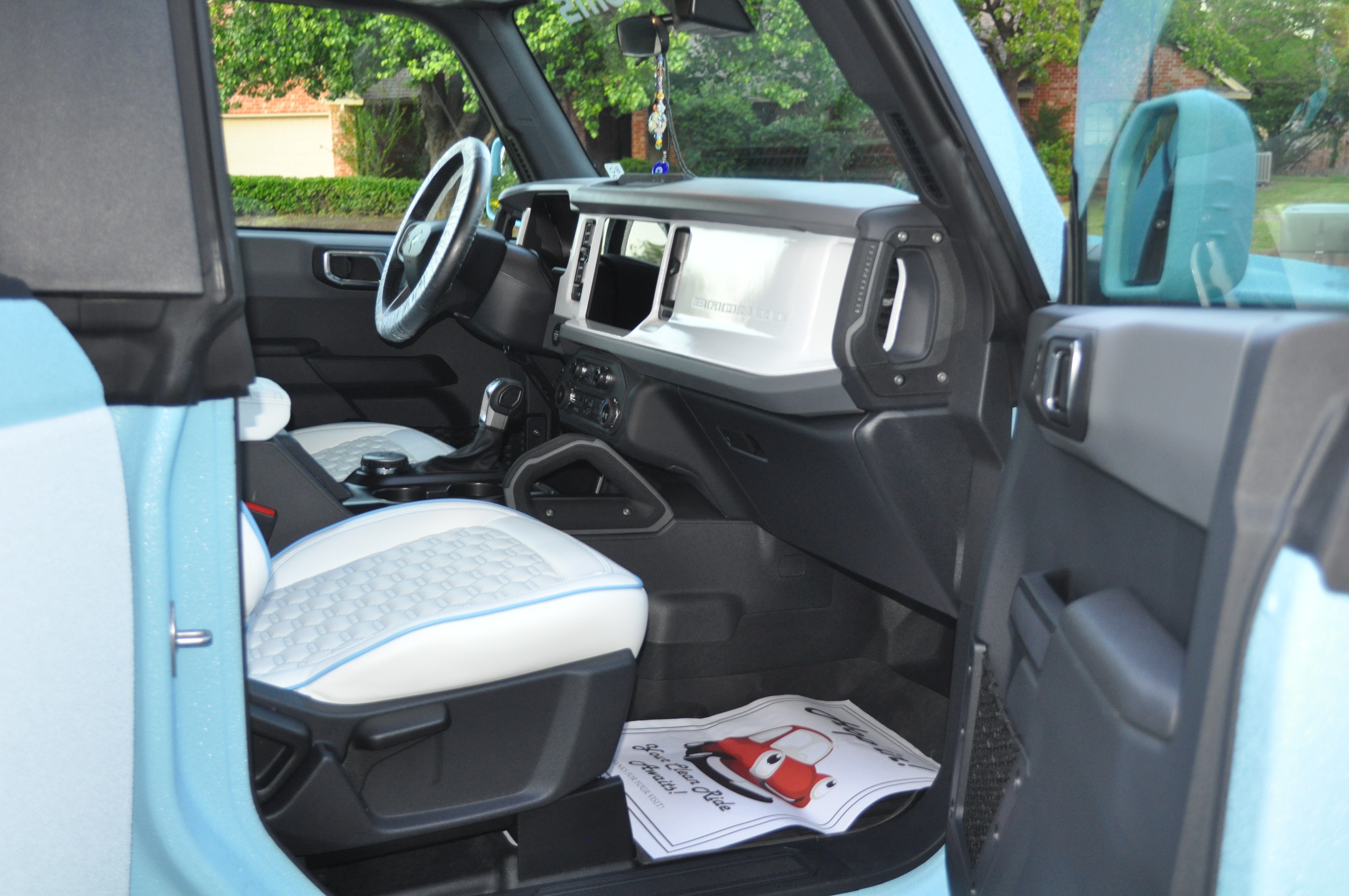 Clean interior of a custom Ford Bronco with white and blue seats.